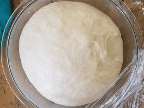 Pizzateig Rezept – aufgegangener Pizzateig in einer Glasschüssel mit Frischhaltefolie